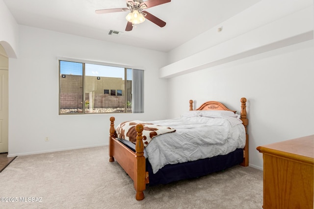 bedroom with light carpet, arched walkways, a ceiling fan, and baseboards