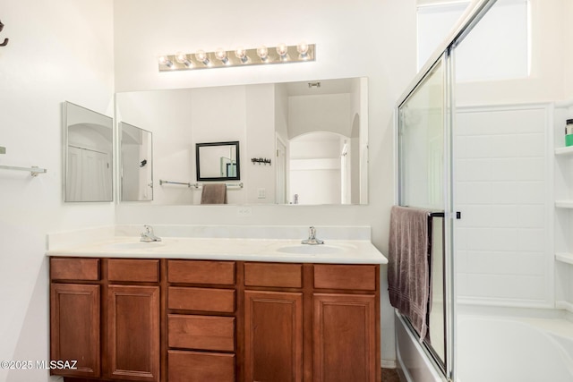 full bathroom with enclosed tub / shower combo, a sink, and double vanity