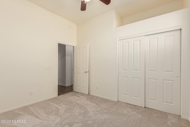 unfurnished bedroom featuring light carpet, a ceiling fan, baseboards, and a closet