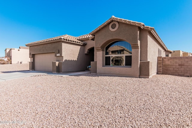 mediterranean / spanish house featuring a garage, concrete driveway, a tile roof, and stucco siding