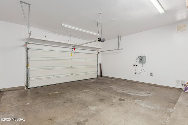 garage featuring baseboards, visible vents, and a garage door opener