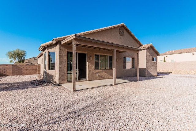 back of house featuring a tile roof, a patio area, a fenced backyard, and stucco siding