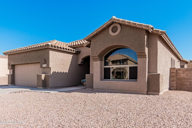 view of front of home featuring an attached garage, a tile roof, and stucco siding