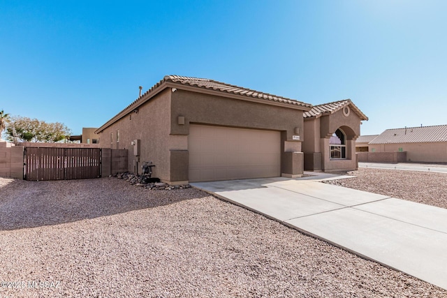 mediterranean / spanish home featuring an attached garage, a tiled roof, concrete driveway, and stucco siding