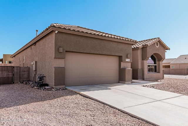 mediterranean / spanish house featuring a garage, fence, a tile roof, driveway, and stucco siding