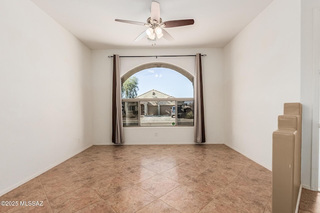 spare room with ceiling fan and baseboards