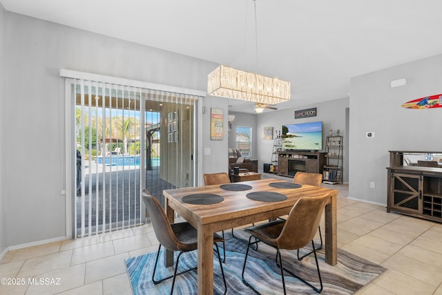 dining area featuring light tile patterned flooring, a fireplace, and baseboards