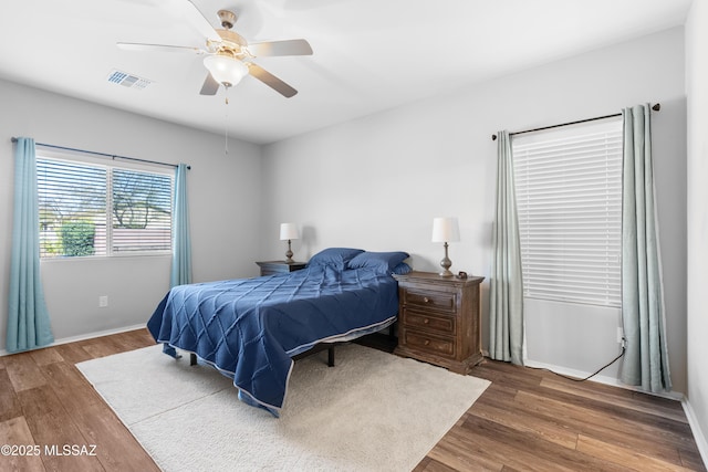 bedroom with baseboards, ceiling fan, visible vents, and wood finished floors