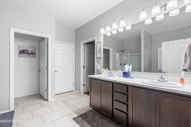 bathroom featuring double vanity, a shower stall, a sink, and tile patterned floors