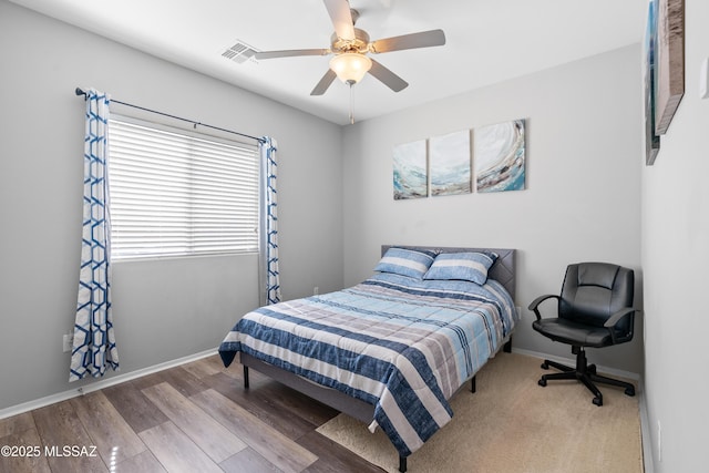 bedroom featuring a ceiling fan, wood finished floors, visible vents, and baseboards