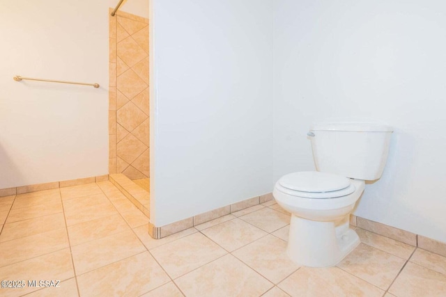 full bath featuring tile patterned flooring, baseboards, a tile shower, and toilet