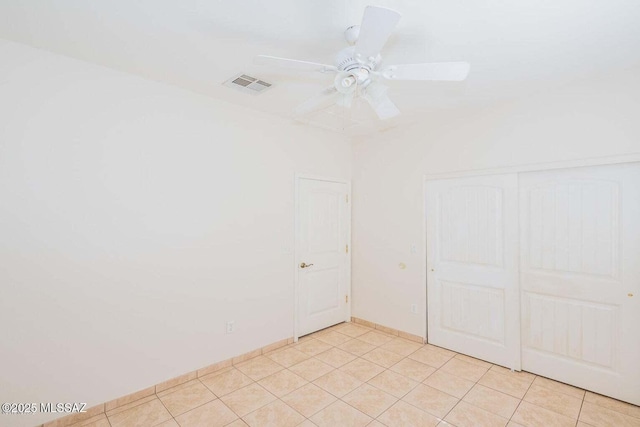 spare room featuring light tile patterned floors, visible vents, and a ceiling fan