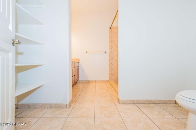 bathroom with tile patterned flooring, toilet, vanity, and a tile shower