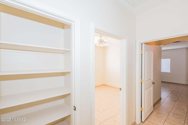 corridor featuring tile patterned floors, arched walkways, and visible vents