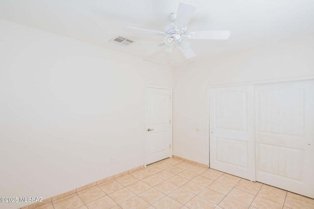 spare room featuring light tile patterned flooring, visible vents, and a ceiling fan