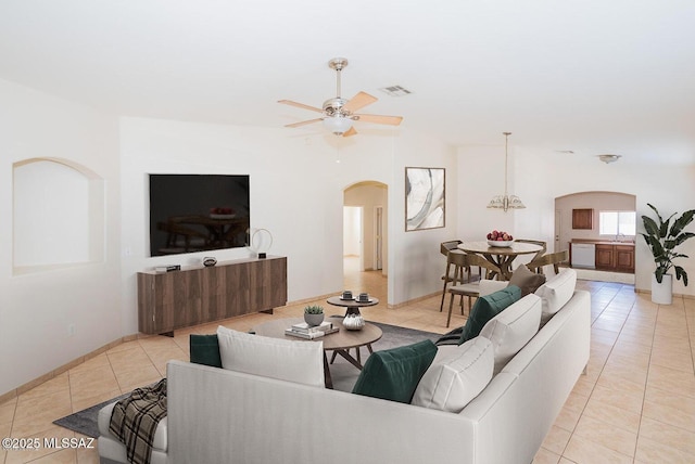 living area with a ceiling fan, light tile patterned floors, visible vents, and arched walkways