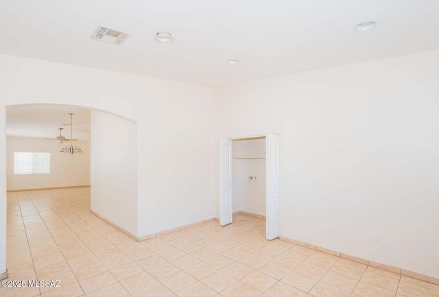 empty room with visible vents, arched walkways, and light tile patterned flooring