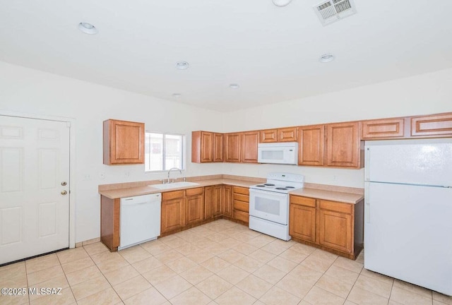 kitchen featuring visible vents, light countertops, brown cabinetry, white appliances, and a sink