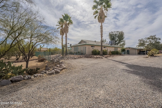 view of front of home with gravel driveway, fence, an attached garage, and central AC unit