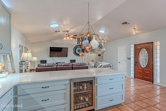 kitchen featuring open floor plan, light tile patterned floors, wine cooler, and vaulted ceiling