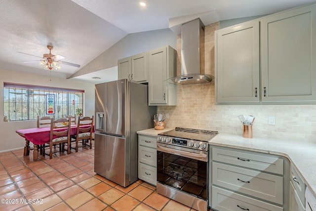 kitchen featuring lofted ceiling, stainless steel appliances, backsplash, ceiling fan, and wall chimney exhaust hood