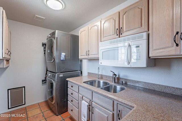 washroom featuring light tile patterned floors, stacked washing maching and dryer, a textured ceiling, a sink, and cabinet space