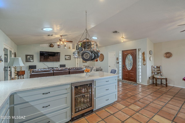 kitchen featuring wine cooler, visible vents, a ceiling fan, open floor plan, and vaulted ceiling