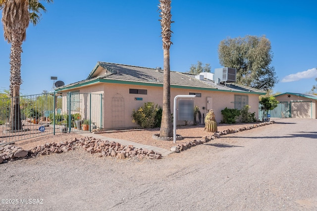 view of front of house featuring stucco siding, central air condition unit, and fence