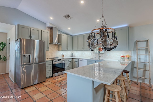 kitchen with visible vents, a peninsula, wall chimney exhaust hood, appliances with stainless steel finishes, and a notable chandelier