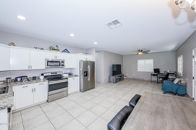 kitchen featuring light stone counters, visible vents, appliances with stainless steel finishes, open floor plan, and white cabinetry