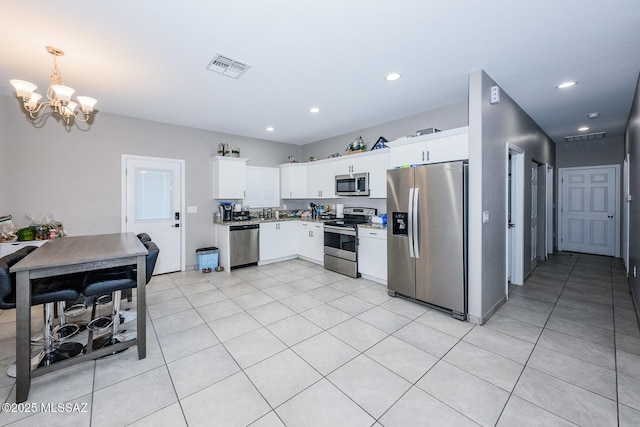 kitchen featuring stainless steel appliances, white cabinets, hanging light fixtures, and visible vents