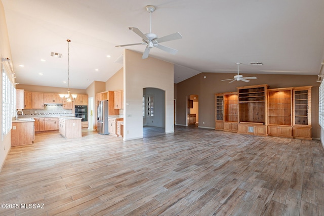unfurnished living room featuring light wood-style floors, ceiling fan with notable chandelier, visible vents, and a sink