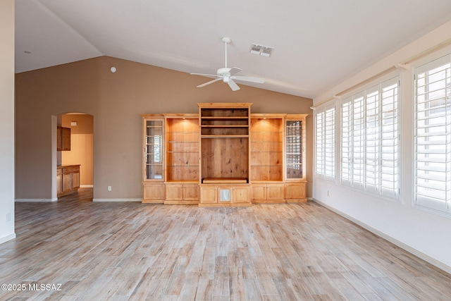 unfurnished living room with vaulted ceiling, a ceiling fan, arched walkways, and light wood-type flooring