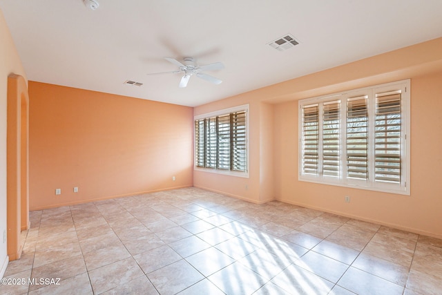 spare room with tile patterned flooring, baseboards, visible vents, and ceiling fan
