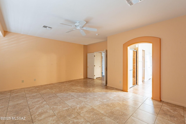 spare room featuring baseboards, arched walkways, visible vents, and ceiling fan