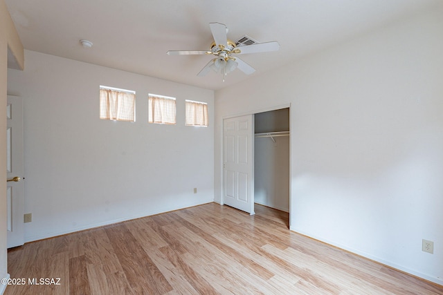 unfurnished bedroom featuring a ceiling fan, light wood-style flooring, visible vents, and a closet