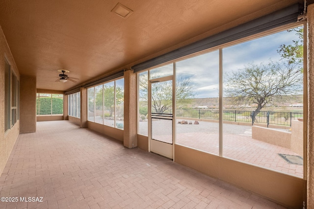 unfurnished sunroom with plenty of natural light, brick floor, and ceiling fan