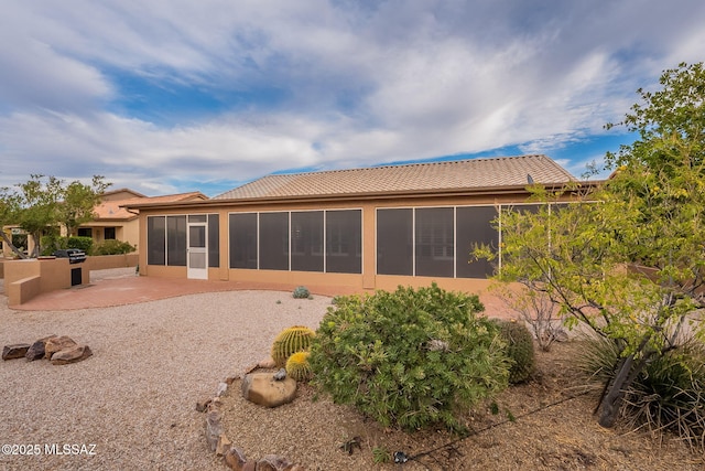 back of property featuring a patio, a tiled roof, a sunroom, and stucco siding