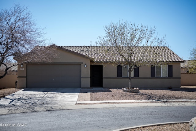 view of front of house with concrete driveway, a tiled roof, an attached garage, and stucco siding