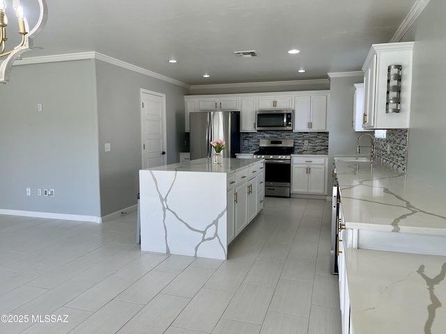 kitchen with backsplash, crown molding, appliances with stainless steel finishes, white cabinetry, and a sink