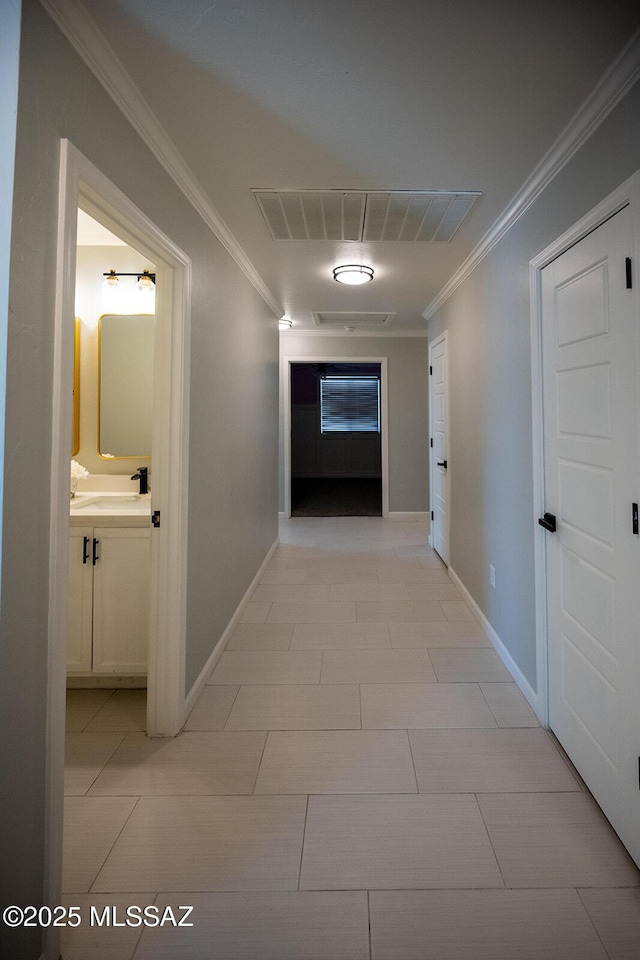 hall with visible vents, baseboards, and crown molding