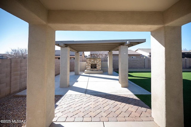 view of patio / terrace with an outdoor stone fireplace and a fenced backyard