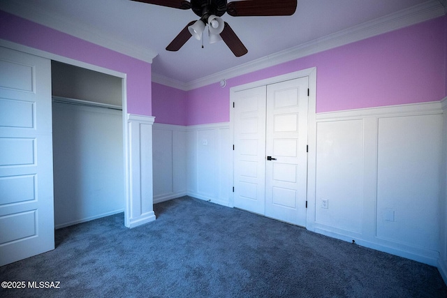 unfurnished bedroom featuring a wainscoted wall, ceiling fan, carpet flooring, and crown molding