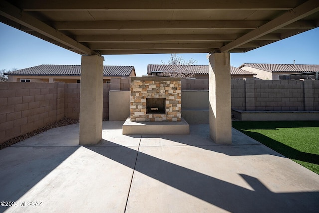 view of patio / terrace with an outdoor stone fireplace and a fenced backyard