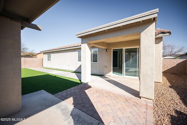 back of house with stucco siding, a patio area, a fenced backyard, and a tiled roof