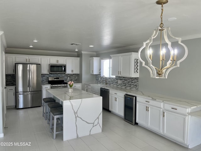 kitchen with tasteful backsplash, a kitchen island, appliances with stainless steel finishes, an inviting chandelier, and white cabinets