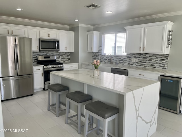 kitchen featuring visible vents, a kitchen island, crown molding, appliances with stainless steel finishes, and white cabinetry