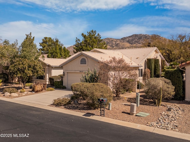 view of front of property with a mountain view, a garage, a tiled roof, concrete driveway, and stucco siding