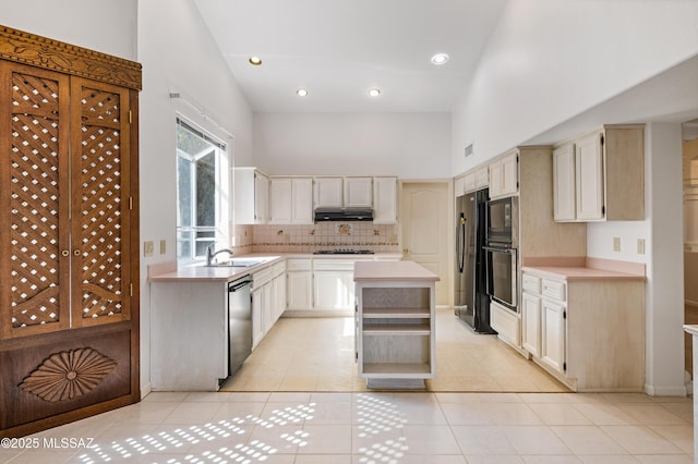 kitchen featuring under cabinet range hood, a high ceiling, light countertops, a center island, and black appliances