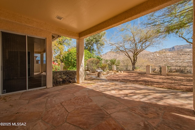 view of patio with visible vents, fence, and a mountain view